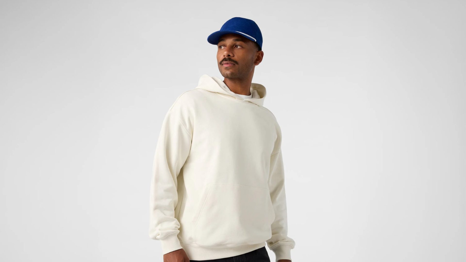 An image of a person wearing a Cream AS colour hoodie and a Blue hat.
